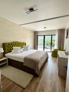 a bedroom with a large bed with a green headboard at Queen Doftana in Teşila