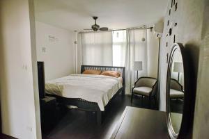 1 dormitorio con cama, silla y espejo en Inner Old Town 196 Chic Guesthouse en Bangkok