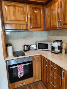 a kitchen with wooden cabinets and a stove and microwave at Apartment Sunny in Casa Del Mare in Varna City
