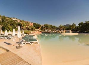 a swimming pool with chairs and umbrellas in a resort at Vue panoramique mer et collines in Grimaud