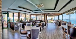 a restaurant with tables and chairs and windows at HOTEL VICKY II in Plomari