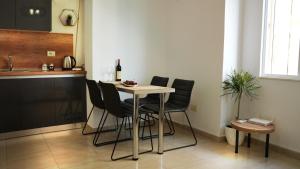una cucina con tavolo, sedie e una bottiglia di vino di High-Tech flat a Durrës