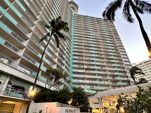 a large building with palm trees in front of it at Serenity Waikiki ! Luxury Ocean Suite ! in Honolulu