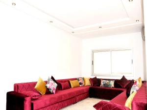 uma sala de estar com um sofá vermelho com almofadas em Beverly Hills California em Kenitra