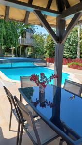 uma mesa com um vaso de flores ao lado de uma piscina em La Pause Cauchoise em Vittefleur