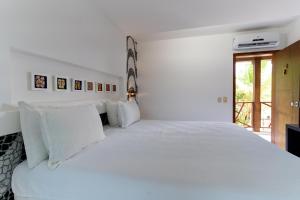 a white bedroom with a large white bed at Galeria e Suites Canto do Sol in Barra Grande
