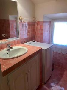 uma casa de banho com um lavatório e azulejos cor-de-rosa em Maison de village 3 chambres avec petite terrasse em Ramatuelle