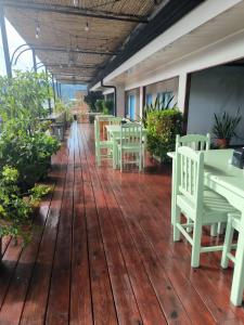 a porch with tables and chairs on a wooden deck at La Hacienda Rooms & Food in Jacó