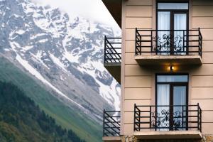 un edificio con balcones y una montaña cubierta de nieve en Panorama Ushba en Mestia