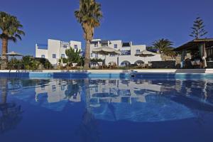a large swimming pool with palm trees and buildings at Fragoulis Village in Parasporos