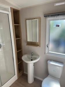 a bathroom with a sink and a toilet and a mirror at Mersea Retreat in West Mersea