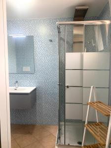 een badkamer met een glazen douche en een wastafel bij Monolocali White Angel Apartments in Porto Cesareo