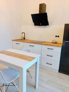 Il comprend une cuisine équipée d'une table blanche et d'un réfrigérateur noir. dans l'établissement Cozy 1 BR in the heart of Astana, à Astana