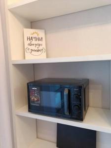 un four micro-ondes noir sur une étagère avec un livre dans l'établissement Cozy 1 BR in the heart of Astana, à Astana