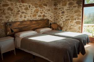 two beds in a room with a stone wall at Mas Ombravella in Mieras