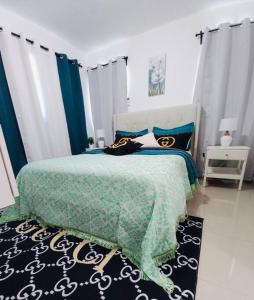 a bedroom with a bed with a green and black comforter at La Cuna de Moises in Santiago de los Caballeros