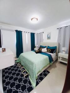 a bedroom with a bed with a green and blue blanket at La Cuna de Moises in Santiago de los Caballeros