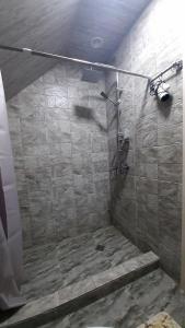 a bathroom with a shower with a stone wall at Kazbegi cottages qabarjina in Stepantsminda