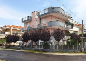 a pink building with trees in front of it at Design Suites Efharis (Sauvignon) in Nea Peramos