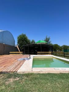 a swimming pool with a wooden deck and a building at COMPLEJO ISABELLA in Villa Amancay