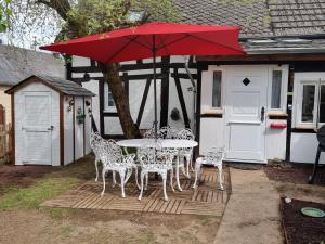 una mesa y sillas con una sombrilla roja en el patio en Fachwerkhaus Hänsel und Gretel, en Hundsdorf
