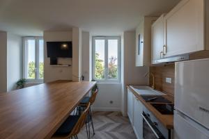 - une cuisine avec un comptoir en bois et quelques fenêtres dans l'établissement L'Évasion - Au coeur de Dax, à Dax