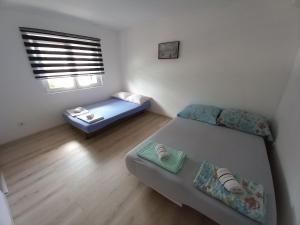a small bedroom with two beds and a window at Apartman Deni in Tuzla
