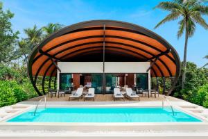 a swimming pool with a large wooden arch over it at The Westin Maldives Miriandhoo Resort in Baa Atoll