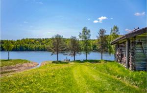 a house on a grass field next to a lake at 2 Bedroom Amazing Home In Vindeln in Vindeln