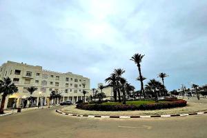une rue avec des palmiers et un grand bâtiment dans l'établissement Appartement en bord de mer, à Monastir