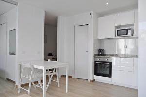 a white kitchen with a white table and a stove at Centro Sitges in Sitges