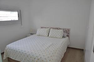 a bedroom with a bed with a comforter and a window at Centro Sitges in Sitges