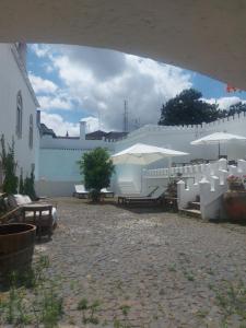 patio z białymi parasolami, stołami i ławkami w obiekcie Loft cidade antiga w mieście Beja