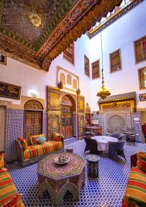 een woonkamer met meubilair en een open haard bij Riad Fes Hayat in Fès
