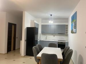 uma cozinha com uma mesa e cadeiras e um frigorífico preto em Xh&S apartment em Durrës