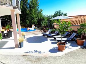een patio met stoelen, een parasol en een zwembad bij House Aronia in Lovran