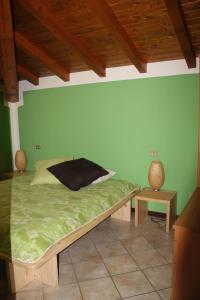 a bed in a room with a green wall at Veranda Beach Apartment in Pianello Del Lario