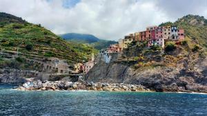 um grupo de edifícios num penhasco junto à água em Agriturismo Angiò nel Cerè em Bracelli