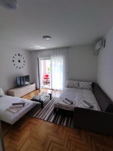 a living room with two beds and a clock on the wall at Apartman MiS Trebinje in Trebinje