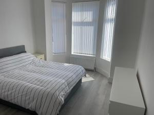 - une chambre blanche avec un lit et 2 fenêtres dans l'établissement Flat 1 15 woodland Road, m18 7HS, à Manchester