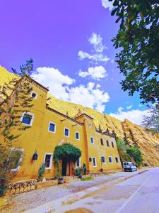 un grande edificio giallo con tetto in erba di Auberge La Fibule Du Dades ad Aït Idaïr