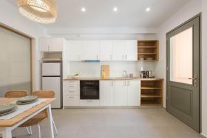 uma cozinha com armários brancos e uma mesa com cadeiras em Lindas Convent Garden Home 1 em Chania Town
