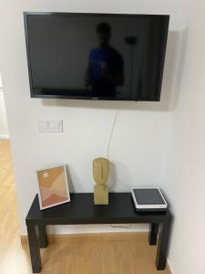 een tv aan een muur met een zwarte tafel bij Ático a 200 metros de la playa in Las Palmas de Gran Canaria