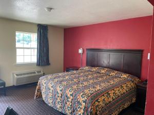 Village Inn في Ada: غرفة نوم بسرير وجدار احمر