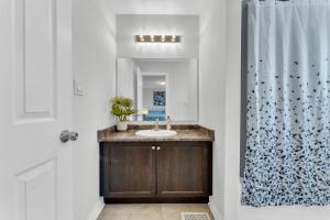 ein Bad mit einem Waschbecken und einem Duschvorhang in der Unterkunft Elevate Your Family Getaway in Oshawa with the brand new Luxury Villa in Oshawa