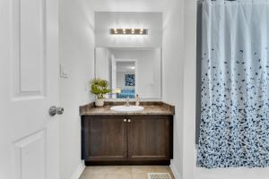 a bathroom with a sink and a shower curtain at Oshawa Family Haven - Luxury 7BR Villa with Cozy Fireplaces & Hot Tub in Oshawa +52 photos
