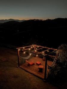 una terraza de madera con dosel con luces. en Canto do Vento Hospedaria, en Santo Antônio do Pinhal