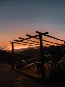 eine Pergola mit Blick auf die Berge bei Sonnenuntergang in der Unterkunft Canto do Vento Hospedaria in Santo Antônio do Pinhal