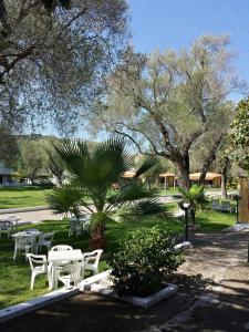 a park with white tables and chairs and trees at Hotel Residence Il Rifugio in Palinuro