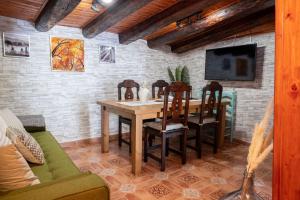 comedor con mesa, sillas y TV en Casa Rural El Burrito de Gredos en Pedro Bernardo